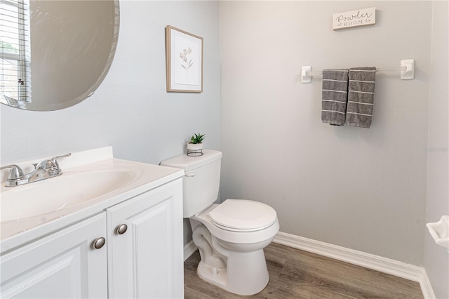 bathroom with baseboards, toilet, wood finished floors, and vanity