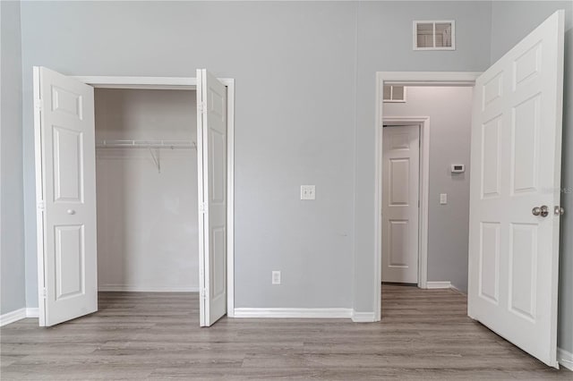 unfurnished bedroom with wood finished floors, a closet, and baseboards