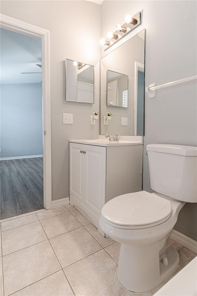 bathroom with toilet, baseboards, vanity, and tile patterned flooring