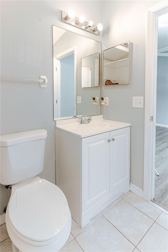 bathroom with toilet, vanity, and tile patterned floors
