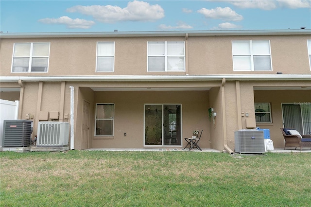 rear view of property with stucco siding, cooling unit, and a lawn
