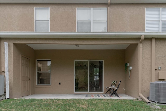 back of house with central air condition unit, stucco siding, and a patio area
