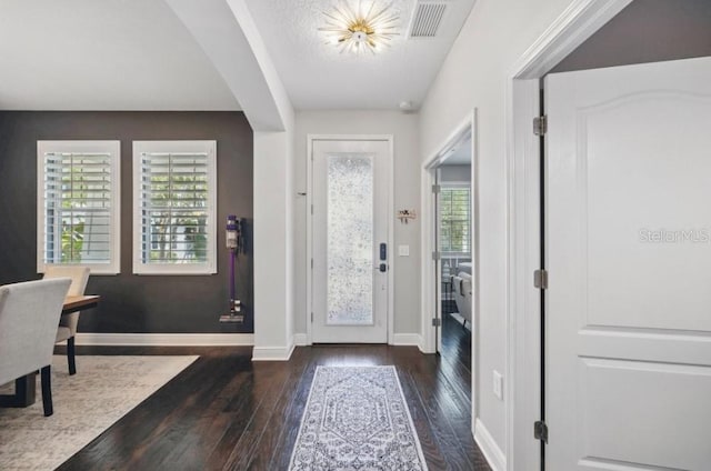 foyer entrance with hardwood / wood-style floors, baseboards, and arched walkways