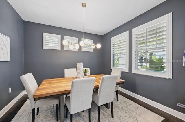 dining room with wood finished floors, a chandelier, and baseboards