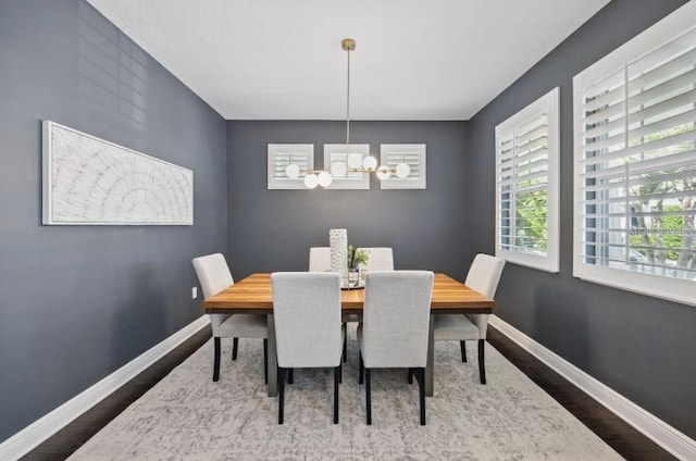 dining space with a chandelier, wood finished floors, and baseboards