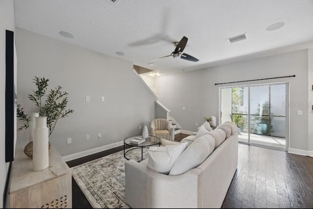 living area featuring dark wood finished floors, a ceiling fan, stairs, and baseboards