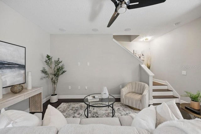 living area with stairway, baseboards, wood finished floors, and a ceiling fan