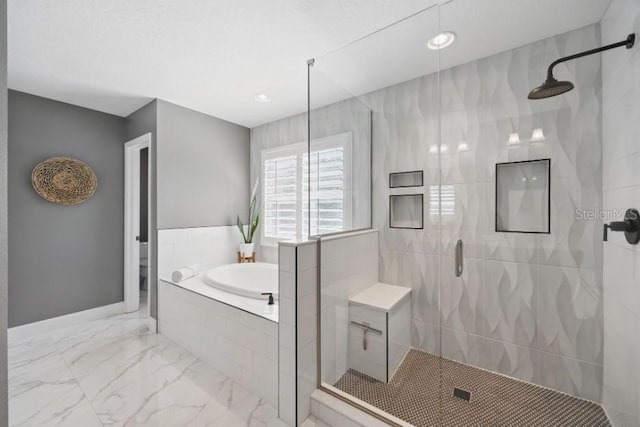 bathroom featuring a garden tub, a shower stall, and marble finish floors