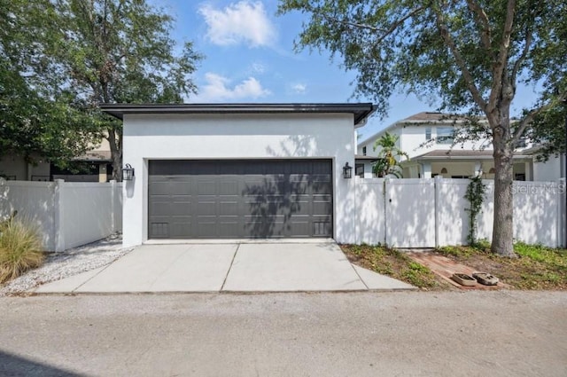 garage with fence and concrete driveway