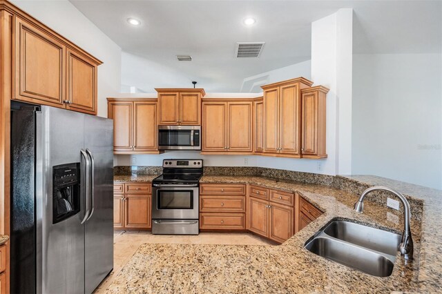 12421 Seabrook Dr, Tampa, FL 33626 - kitchen featuring appliances with stainless steel finishes, a sink, brown cabinets, stone countertops, and recessed lighting