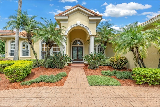entrance to property featuring french doors, a tile roof, and stucco siding