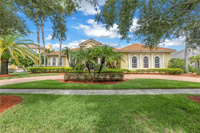 mediterranean / spanish home featuring curved driveway, stucco siding, and a front yard