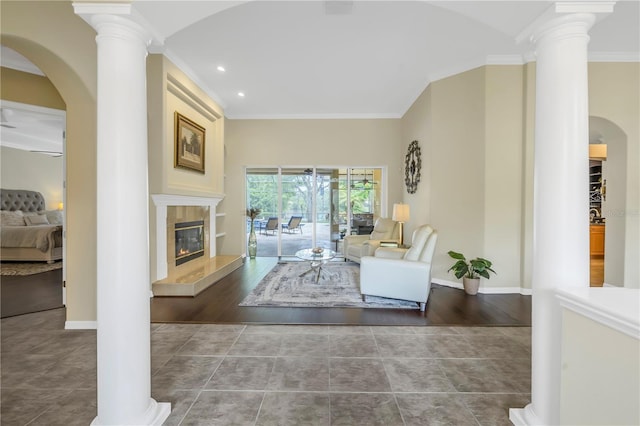 tiled living area featuring ornate columns, crown molding, baseboards, recessed lighting, and arched walkways