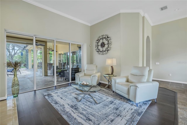 living area featuring arched walkways, ornamental molding, baseboards, and wood finished floors