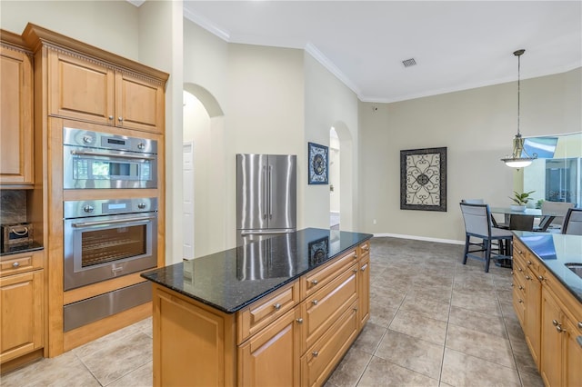 kitchen featuring stainless steel appliances, arched walkways, ornamental molding, a kitchen island, and dark stone counters