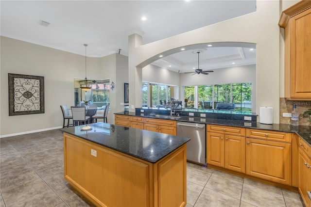 kitchen featuring dishwasher, a sink, arched walkways, a ceiling fan, and a center island
