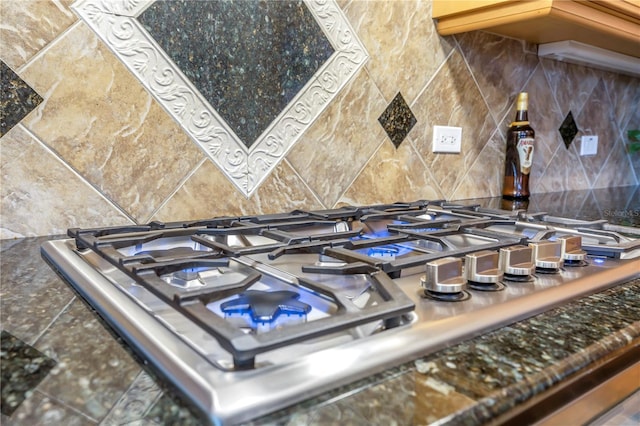 kitchen view of stainless steel gas stovetop and tasteful backsplash