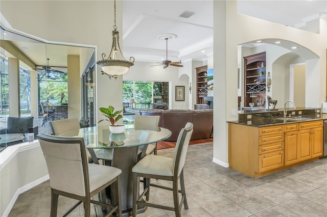 dining room with light tile patterned flooring, ceiling fan, arched walkways, and baseboards