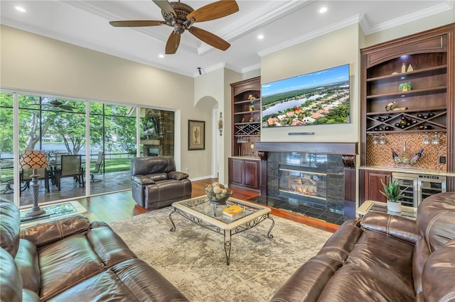 living area featuring a fireplace, wood finished floors, a ceiling fan, arched walkways, and a high ceiling