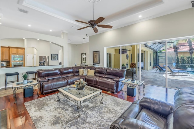 living room featuring arched walkways, ceiling fan, hardwood / wood-style floors, recessed lighting, and a tray ceiling