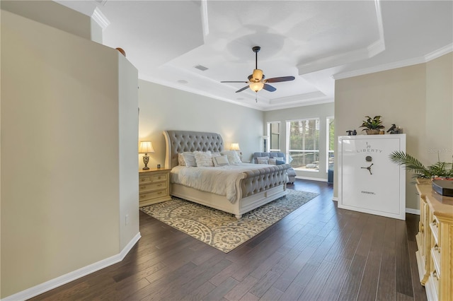 bedroom featuring a tray ceiling, dark wood-style flooring, baseboards, ornamental molding, and ceiling fan