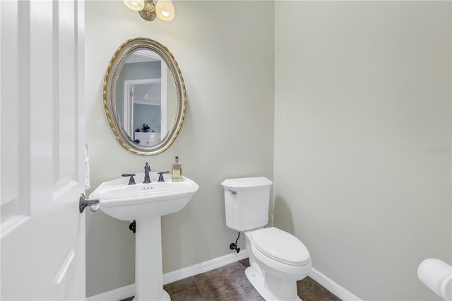 bathroom featuring toilet, baseboards, tile patterned flooring, and a sink