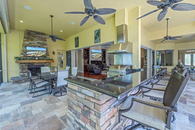 view of patio featuring an outdoor stone fireplace, ceiling fan, an outdoor kitchen, and grilling area