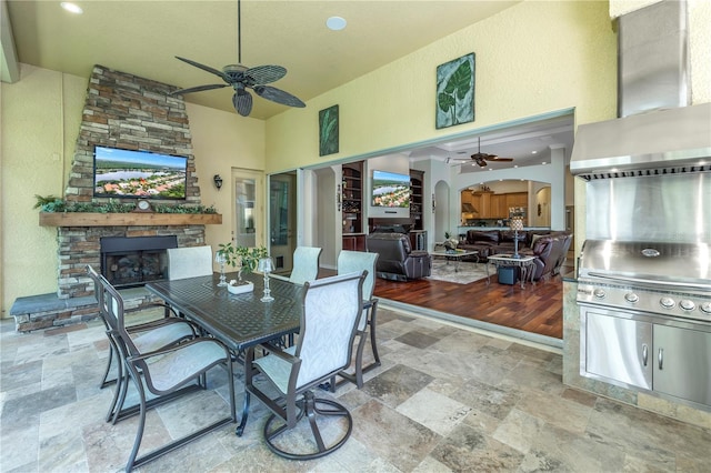view of patio featuring a fireplace, ceiling fan, and outdoor dining space