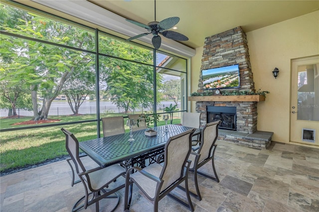 sunroom / solarium with a fireplace, ceiling fan, and outdoor dining space