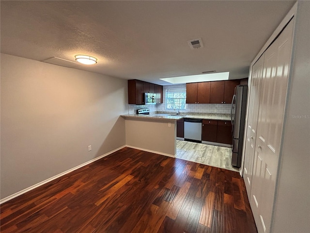 14446 Reuter Strasse Cir Unit 3, Tampa, FL 33613 - kitchen with stainless steel appliances, light wood finished floors, light countertops, dark brown cabinets, and decorative backsplash