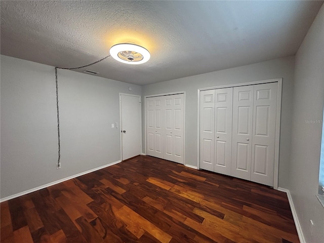 14446 Reuter Strasse Cir Unit 3, Tampa, FL 33613 - unfurnished bedroom featuring dark wood finished floors, multiple closets, baseboards, and a textured ceiling
