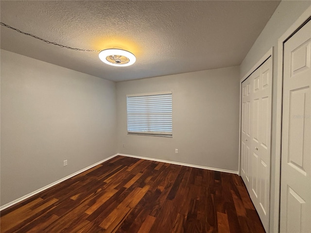 14446 Reuter Strasse Cir Unit 3, Tampa, FL 33613 - unfurnished bedroom featuring dark wood finished floors, baseboards, and a textured ceiling