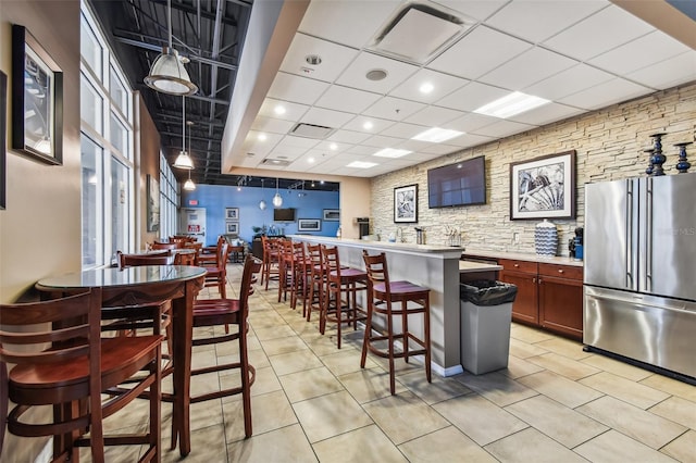 6140 Marina Cove Way S, Saint Petersburg, FL 33712 - kitchen with high quality fridge, a paneled ceiling, a kitchen bar, light countertops, and light tile patterned flooring