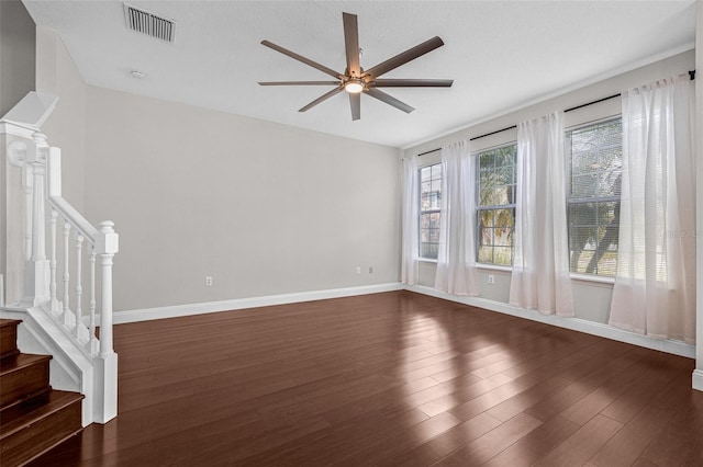 spare room with a ceiling fan, stairway, dark wood-type flooring, and baseboards
