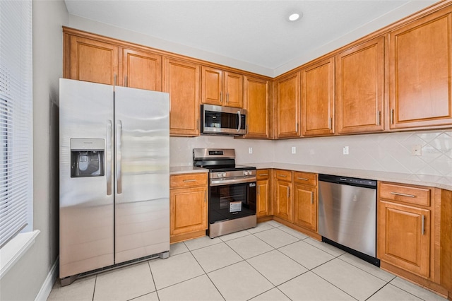 kitchen with appliances with stainless steel finishes, brown cabinetry, light countertops, and recessed lighting