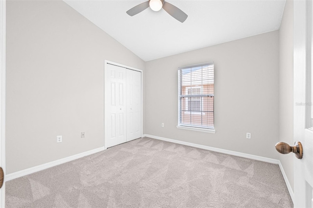 unfurnished bedroom featuring carpet flooring, a closet, lofted ceiling, baseboards, and ceiling fan