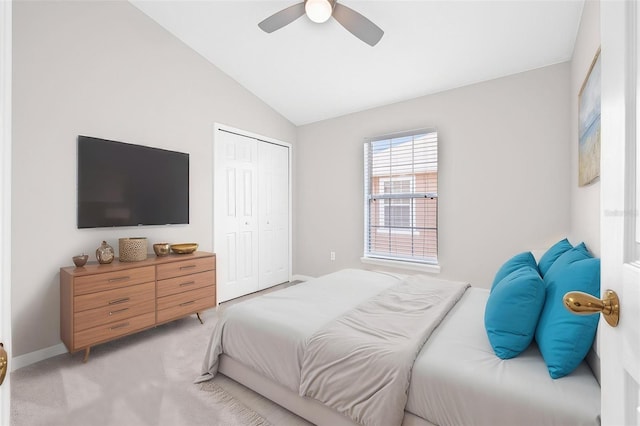 bedroom with a closet, light carpet, vaulted ceiling, ceiling fan, and baseboards
