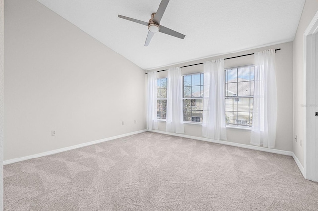 carpeted empty room with ceiling fan, vaulted ceiling, and baseboards