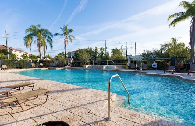 community pool with fence and a patio