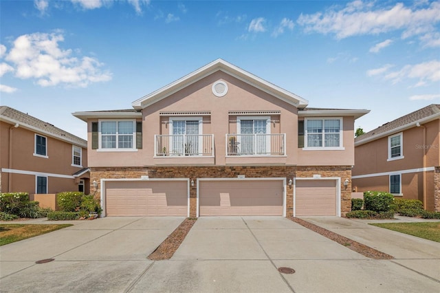 townhome / multi-family property with concrete driveway, stucco siding, stone siding, and an attached garage