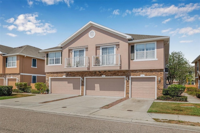 townhome / multi-family property featuring stone siding, driveway, a garage, and stucco siding