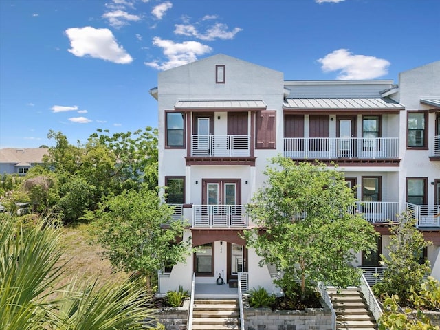 946 Highland Ave Unit 24, Dunedin, FL 34698 - view of property featuring a standing seam roof, stairs, stucco siding, and metal roof