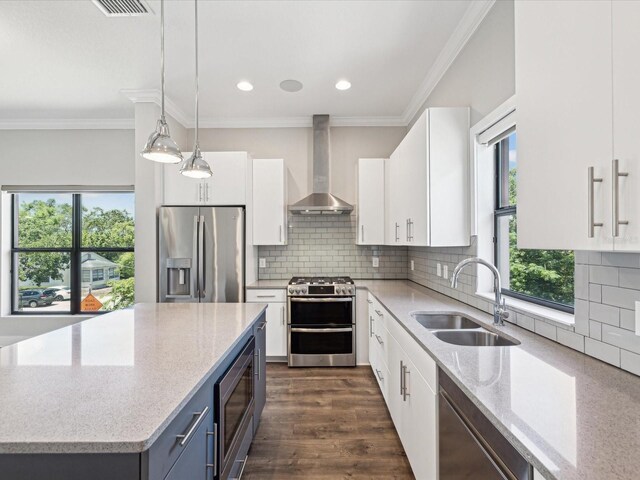 946 Highland Ave Unit 24, Dunedin, FL 34698 - kitchen featuring wall chimney exhaust hood, stainless steel appliances, a sink, light stone counters, and crown molding