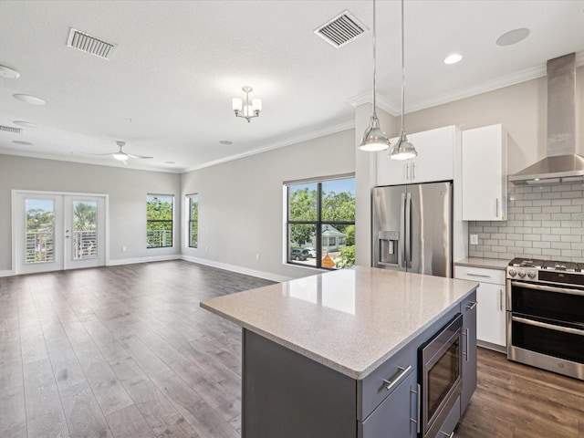 946 Highland Ave Unit 24, Dunedin, FL 34698 - kitchen featuring stainless steel appliances, wall chimney exhaust hood, ceiling fan, white cabinetry, and decorative backsplash