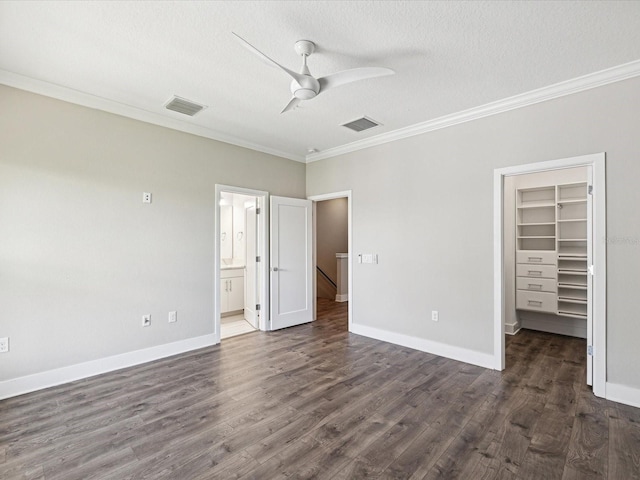 946 Highland Ave Unit 24, Dunedin, FL 34698 - unfurnished bedroom featuring crown molding, a textured ceiling, a spacious closet, dark wood-type flooring, and a closet