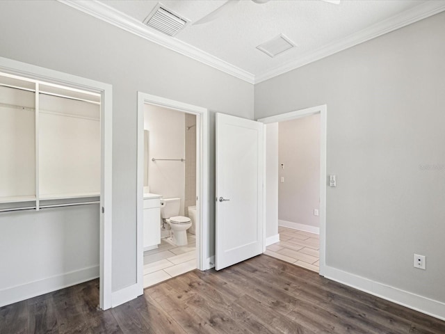 946 Highland Ave Unit 24, Dunedin, FL 34698 - unfurnished bedroom with ornamental molding, a closet, wood finished floors, baseboards, and connected bathroom