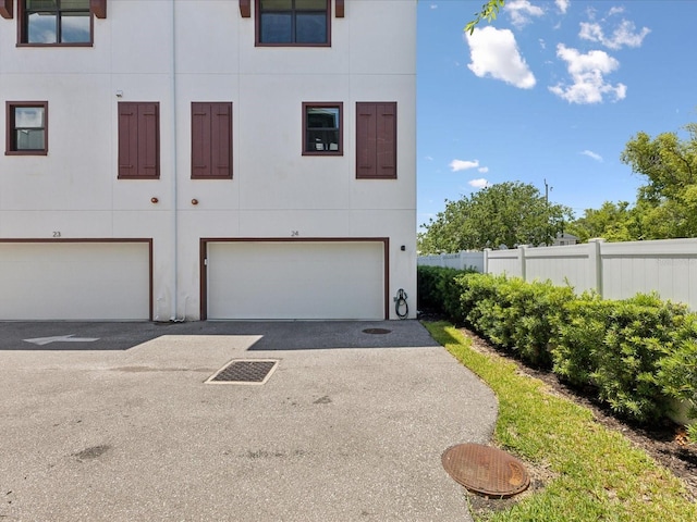 946 Highland Ave Unit 24, Dunedin, FL 34698 - view of front of home with fence, stucco siding, an attached garage, and asphalt driveway