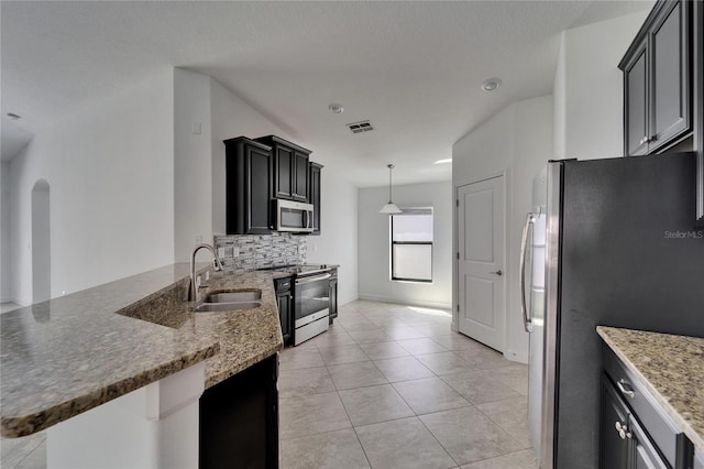 12055 Cardinal Flower Dr, Riverview, FL 33579 - kitchen with appliances with stainless steel finishes, a sink, a peninsula, decorative backsplash, and light tile patterned floors