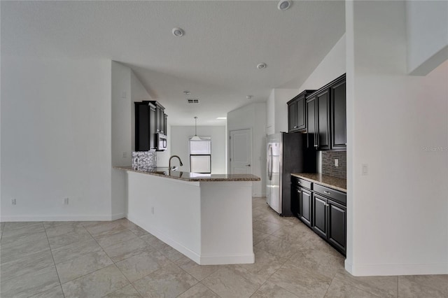 12055 Cardinal Flower Dr, Riverview, FL 33579 - kitchen with decorative backsplash, dark cabinetry, freestanding refrigerator, and stone counters