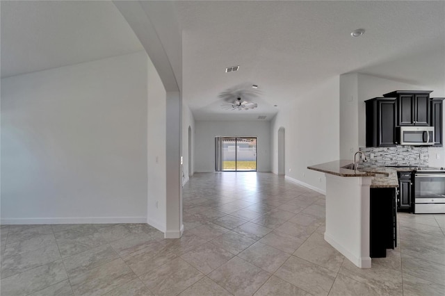 12055 Cardinal Flower Dr, Riverview, FL 33579 - kitchen featuring appliances with stainless steel finishes, arched walkways, dark cabinetry, open floor plan, and dark stone countertops